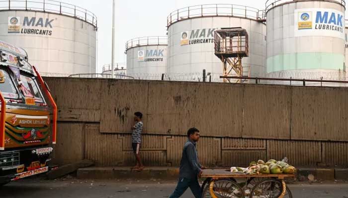 A man pushes his cart as he walks past Bharat Petroleum’s storage tankers in Mumbai, India. — AFP/File
