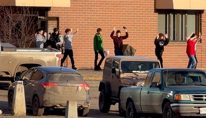 Students walk out of the school building with their hands up after an assailant opened fire at a high school in the town of Tumbler Ridge, British Columbia, Canada, February 10, 2026. — Reuters