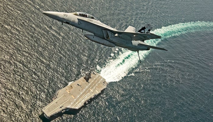 An F/A-18F Super Hornet jet flies over the USS Gerald R Ford as the US Navy aircraft carrier tests its EMALS magnetic launching system.— Reuters/File