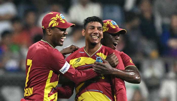West Indies Gudakesh Motie (C) celebrates with Akeal Hosein (L) and Shamar Joseph after taking the wicket of Zimbabwes Tashinga Musekiwa during the 2026 ICC Mens T20 Cricket World Cup Super Eights match between West Indies and Zimbabwe at the Wankhede Stadium in Mumbai on February 23, 2026. — AFP