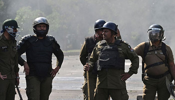 Policemen stand guard as Pakistan Tehreek-e-Insaf party activists and supporters protest against the arrest of Imran Khan in Lahore on May 11, 2023. — AFP