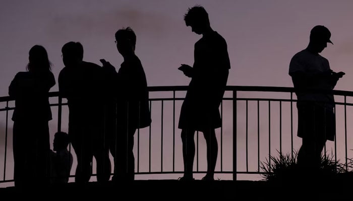 People use their mobile phones, ahead of new law banning social media for users under 16. — Reuters/File
