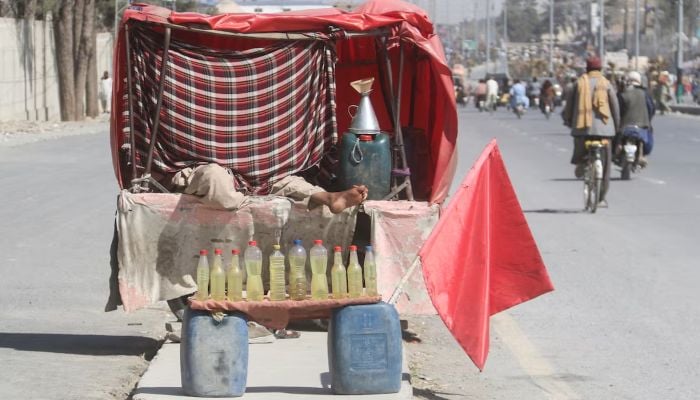 A man rests while selling bottles filled with petrol, brought from Iran, amid the U.S.-Israel conflict with Iran, at a roadside stall in Quetta, Pakistan, March 4, 2026. — Reuters