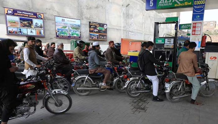 People wait for their turn to get fuel at a petrol station. — Reuters/File
