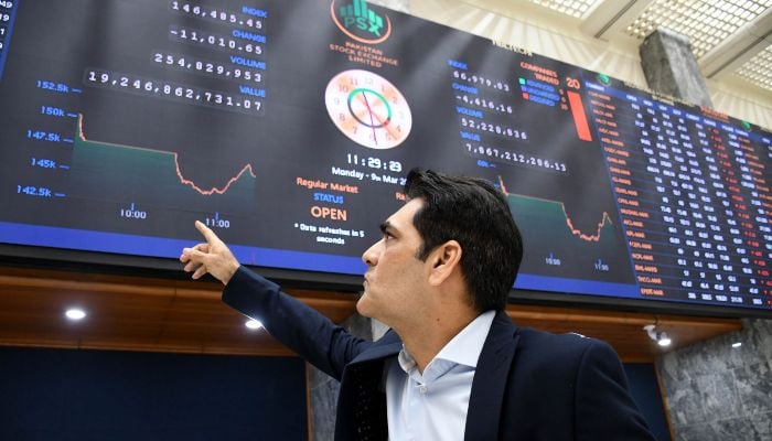 An investor monitors a digital board showing share prices at the Pakistan Stock Exchange (PSX) in Karachi on March 9, 2026. — AFP