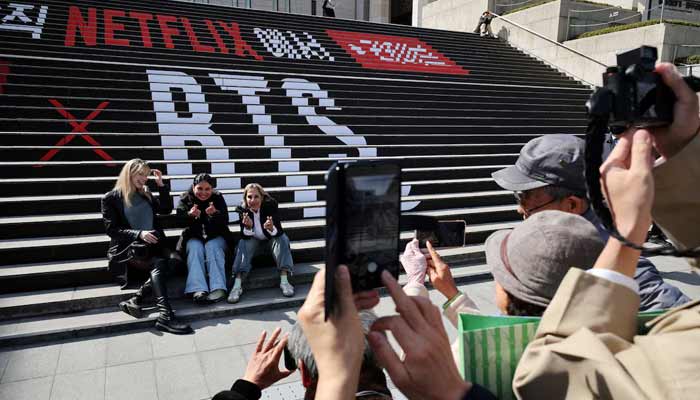 Fans of K-pop group BTS pose for photographs with an advertisement promoting BTS The Comeback Live Arirang concert in central Seoul, South Korea, March 19, 2026.— Reuters
