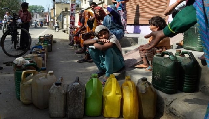 A child sits with others as they wait their turn to get subsidised kerosene oil outside a government fair price shop in Alwar district of Rajasthan.— AFP/File