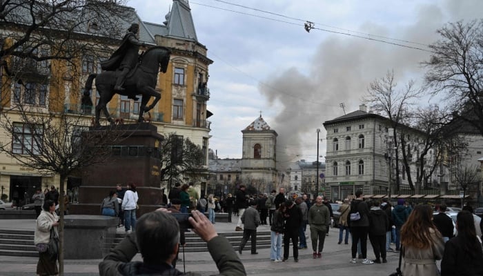 People look at smoke rising from a burning building following a Russian drone attack in Lviv, Ukraine, March 24, 2026. — AFP