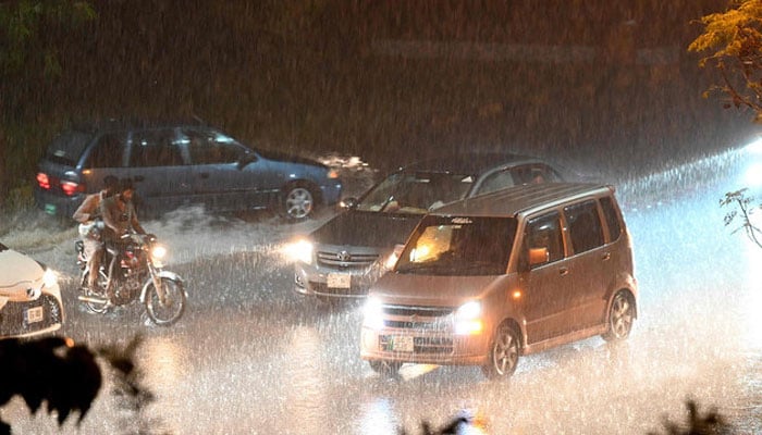 Commuters make their way through heavy rain in Islamabad on July 26, 2023, braving the monsoon downpour to reach their destinations. — AFP