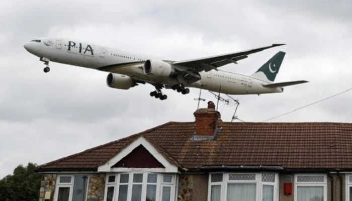 A Pakistan International Airlines (PIA) Boeing 777 comes in over houses to land at Heathrow Airport in west London on June 8, 2020. — AFP