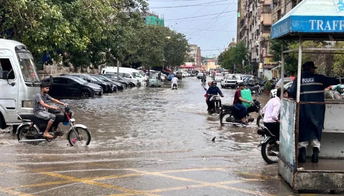 A traffic police officer manages the flow of vehicles as commuters navigate a waterlogged road following heavy rainfall in Karachi on April 2, 2026. — Geo.tv