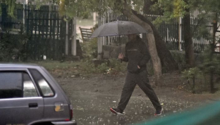 A man holds an umbrella on his way at a road during heavy rain in Islamabad, March 15, 2026. — Online