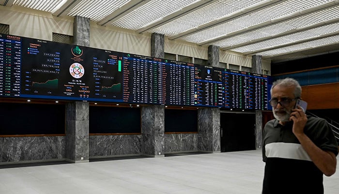 A stock broker walks past a digital board showing share prices at the Pakistan Stock Exchange (PSX) in Karachi on March 25, 2026. — AFP