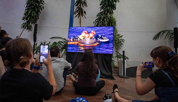 People watch a live broadcast of the return of the Artemis II crew members to Earth at the San Diego Air and Space Museum during a watch party for the crews splash down in the Pacific Ocean, in San Diego, California, on April 10, 2026. — AFP
