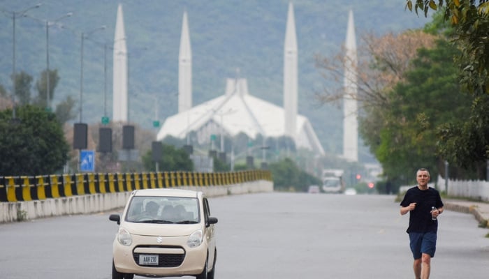 A man jogs along a road early in the morning near the Faisal Masjid ahead of the delegations arrival from the United States and Iran in Islamabad, April 11, 2026. — Reuters