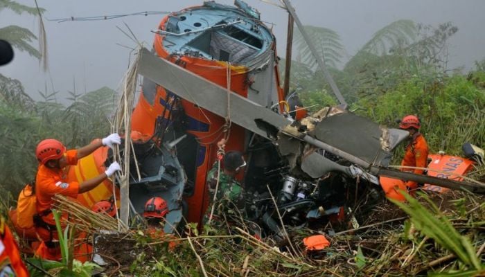 Members of an Indonesian search and rescue team examine the wreckage of a team helicopter on July 4, 2017, after it crashed in Temanggung, central Java. — AFP