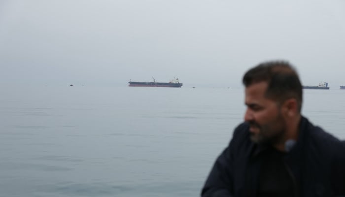 A man stands onshore with the Greek-flagged crude oil tanker Asahi Princess off the coast of the Syrian Baniyas port refinery, along the Mediterranean Sea, April 15, 2026. — AFP