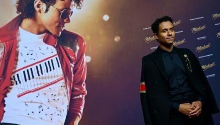 Michael Jacksons nephew Jaafar Jackson poses for a picture beside his poster starring as the King of Pop from the movie Michael, at a premier night. — AFP