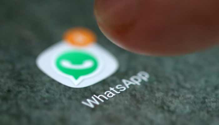 A man poses with a smartphone in front of displayed Whatsapp logo. — Reuters/File