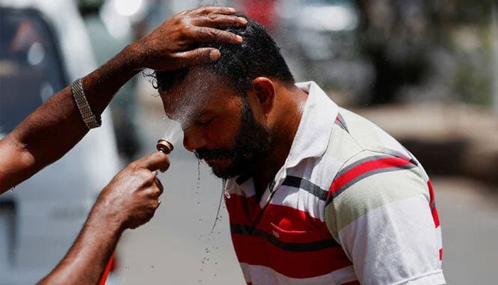 A man receives a spray of cold water to avoid heat during a hot day, along a road in Karachi, on April 22, 2025. — Reuters