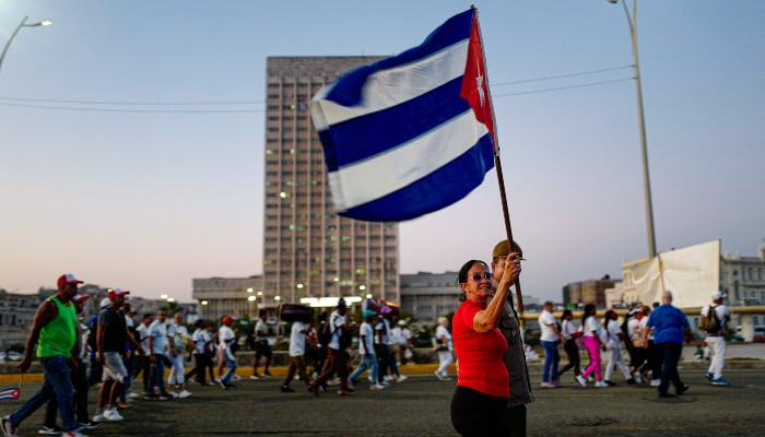 A woman marches holding a Cuban national flag along Havanas waterfront to mark International Workers Day at the Anti-Imperialist Platform in front of the US Embassy in Havana on May 1, 2026. — AFP
