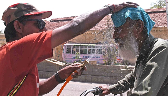 An NGO volunteer sprays water on a passerby to cool him off on a hot summer day in Karachi, on May 4, 2026. — Online