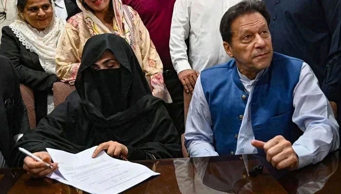 PTI founder Imran Khan (right) pictured along with his wife Bushra Bibi (centre) as he signs surety bonds for bail in various cases, at the registrars office in the Lahore High Court on July 17, 2023. — AFP