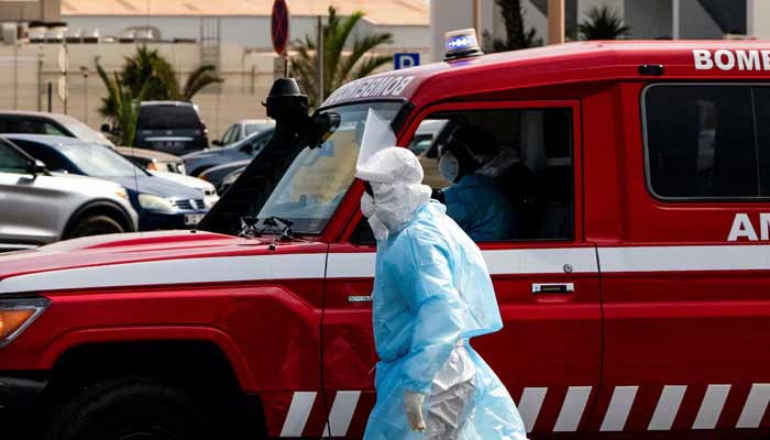 A person in protective clothing walks next to an ambulance during an evacuation operation of suspected hantavirus patients, following an outbreak on the cruise ship MV Hondius, in Praia, Cape Verde, May 6, 2026. — Reuters