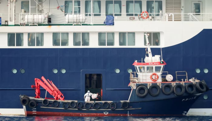 A person wearing personal protective equipment (PPE) on a boat transfers a package to the cruise ship MV Hondius at the port of Granadilla de Abona after being affected by a hantavirus outbreak in Tenerife, Spain, May 10, 2026. — Reuters