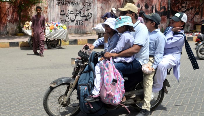 Students wearing caps as they head to school on a motorcycle in Hyderabad, on May 6, 2026. — INP