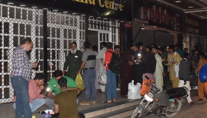 People stand outside a closed market in Lahore on May 7, 2026. — Online