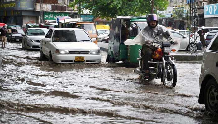Commuters passing through stagnant rain water accumulated at Khyber Bazar Pull area.— APP