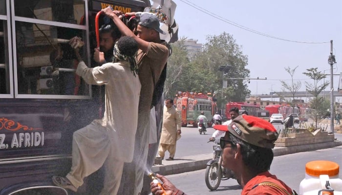 A volunteer sprays water on passerby to cool off on a hot summer day in Karachi, May 4, 2026. — Online