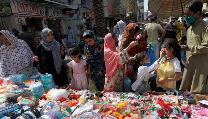 Women and children shop from a stall in a market in Karachi. — Reuters/File