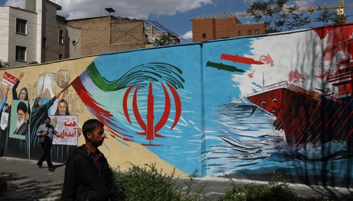People walk on a street near a mural featuring an image of the late Supreme Leader of Iran, Ayatollah Ali Khamenei, in Tehran, Iran, May 18, 2026. — Reuters