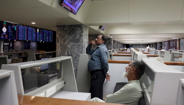 Stock brokers monitor news on television screen at a booth, during a trading session at the Pakistan Stock Exchange, in Karachi, July 3, 2023. — Reuters