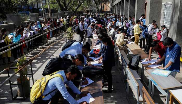 Job seekers fill up forms as others line up for registration during a job fair in Chinchwad, India, February 7, 2019. Picture taken February 7, 2019.— Reuters/File