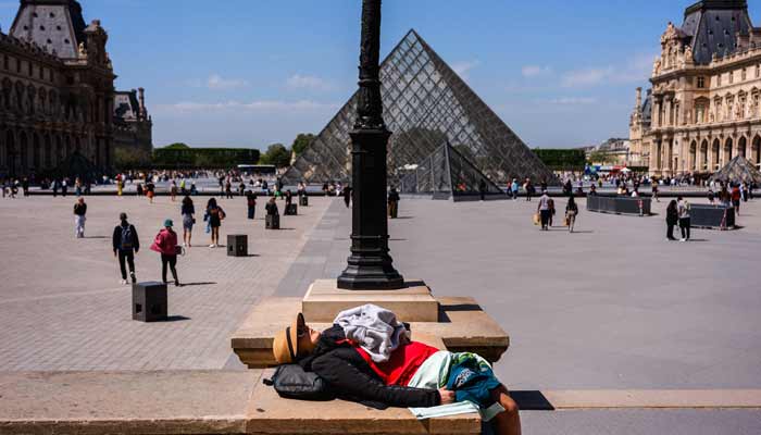A tourist rests in the courtyard of the Louvre Museum, near the Louvre Pyramid designed by Chinese-American architect Ieoh Ming Pei, in Paris on April 28, 2026.— AFP