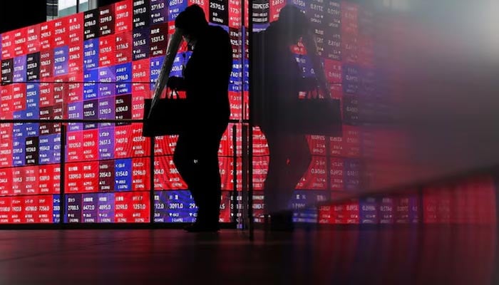 A man walks in front of an electronic screen displaying Japans Nikkei stock prices quotation board inside a conference hall in Tokyo, Japan, April 27, 2026. — Reuters