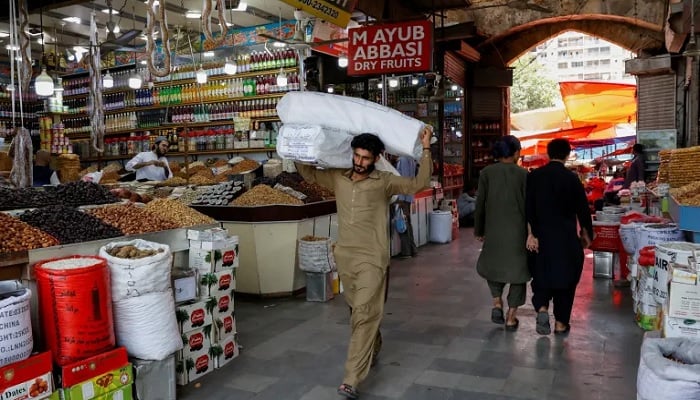A man walks with sacks of supplies on his shoulder to deliver to a nearby shop at a market. — Reuters/File