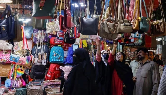 People look at handbags on display outside shops in a market in Karachi on April 19, 2023. — Reuters