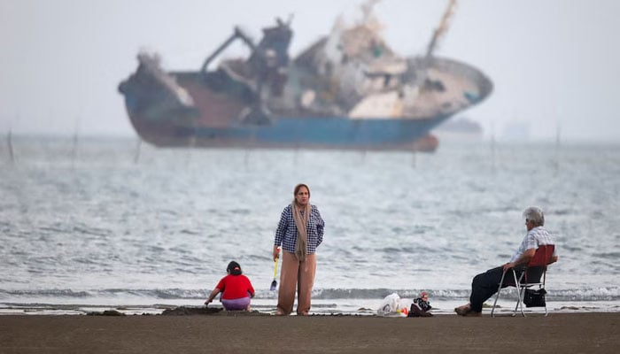 People gather on a beach, as a vessel in the Strait of Hormuz is visible, near the beach of Bandar Abbas, Iran, May 31, 2026. — Reuters/File