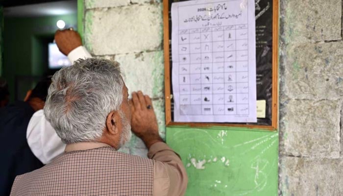An elderly voter carefully looks at the election symbols on the ballot paper before casting his vote during the Gilgit-Baltistan General Elections, June 7, 2026. — APP