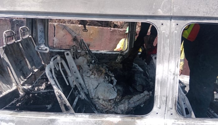 Rescue workers inspect the burnt-out tourist van involved in the deadly crash near Khajut on Islamabad-Murree Expressway, Murree, June 10, 2026. — Reporter