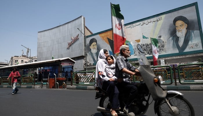 People ride past a mural depicting the late leader of the Islamic Revolution, Ayatollah Ruhollah Khomeini, and the late Irans Supreme Leader Ayatollah Ali Khamenei, on a street in Tehran, Iran, June 9, 2026. — Reuters