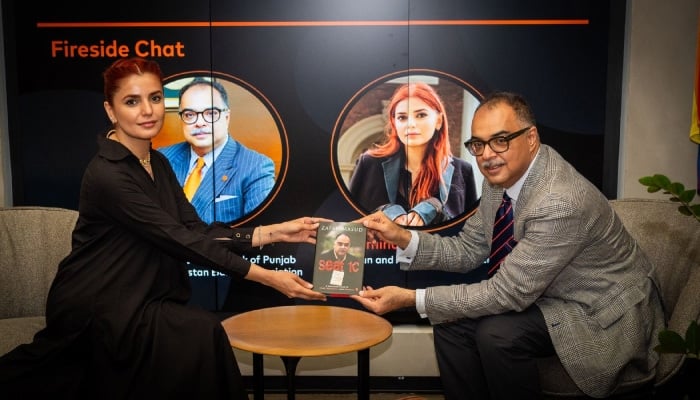 Zafar Masud is presenting his book, Seat 1C, to Momina Mustehsan. — The Pakistan Initiative