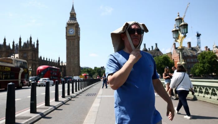 A man covers his head with a bag as he walks down Westminster Bridge during the hot summer weather in London, Britain, June 19, 2026. — Reuters