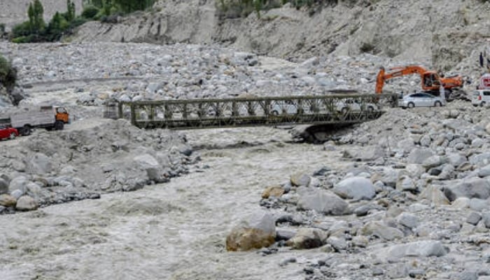 Locals and tourists drive through a temporary bridge after the main bridge was swept away by a lake outburst because of a melting glacier, in Hassanabad village in Gilgit-Baltistan, June 9, 2022. — AFP